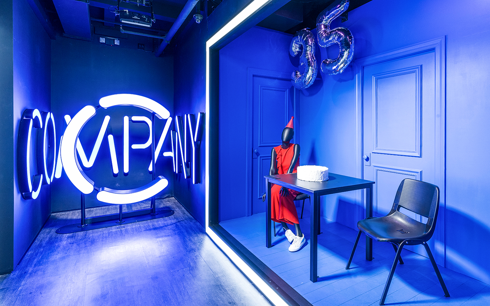 Neon "Company" sign and mannequin in red dress with cake at Museum of Broadway exhibit.