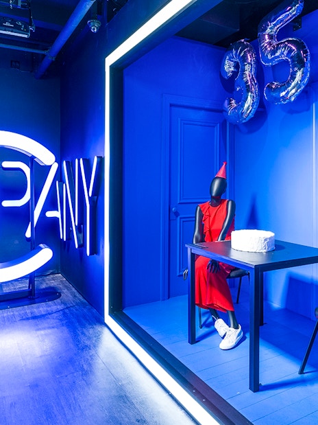 Neon "Company" sign and mannequin in red dress with cake at Museum of Broadway exhibit.