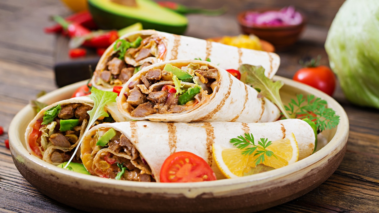 Burrito wraps with various fillings on a wooden board