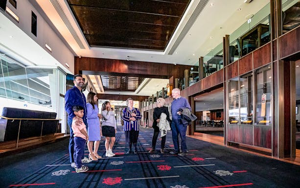 Group touring Melbourne Cricket Ground interior hallway.