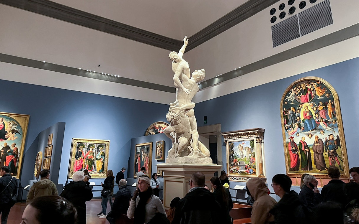 Accademia Gallery visitors viewing Renaissance paintings and a prominent sculpture.