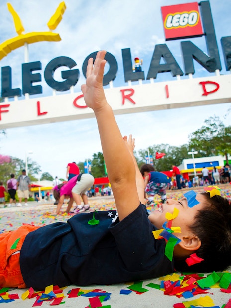 Child playing with confetti at LEGOLAND Florida entrance, Orlando Explorer City Pass.