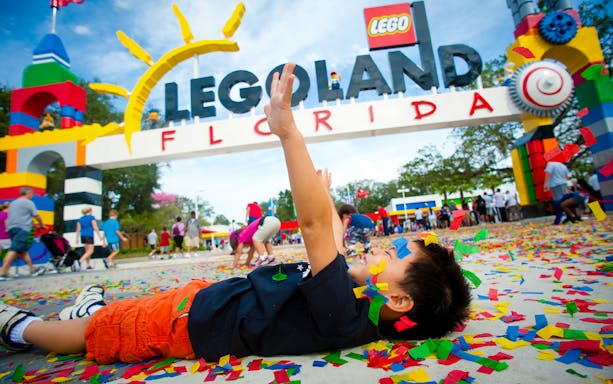 Child playing with confetti at LEGOLAND Florida entrance, Orlando Explorer City Pass.