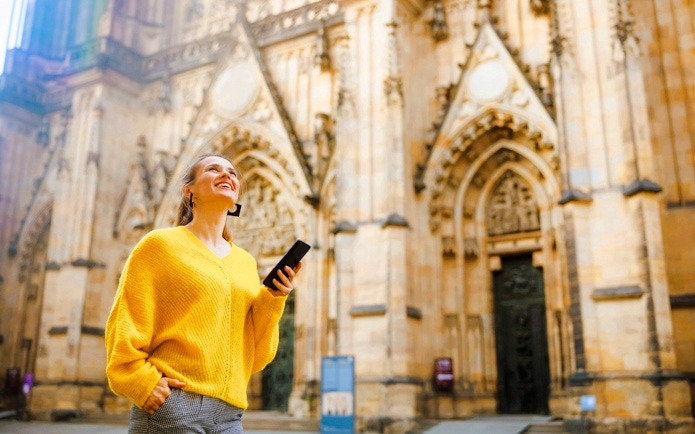 Visitor using audio guide at Prague Castle entrance.