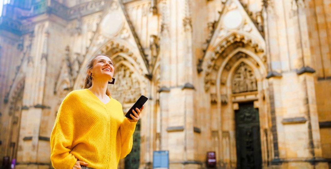 Visitor using audio guide at Prague Castle entrance.