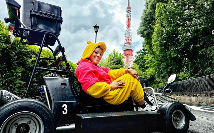 Lady in costume on go-kart near Tokyo Tower during tour.