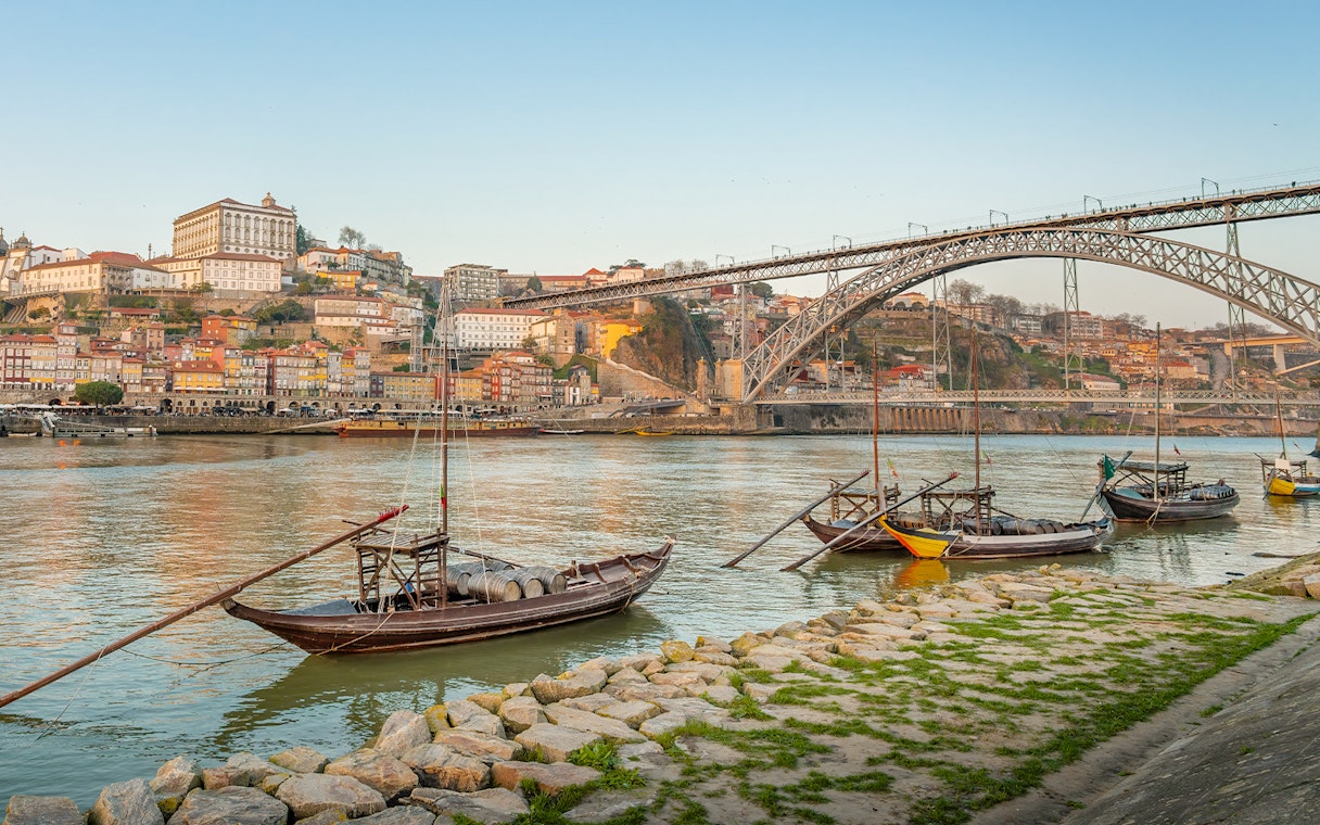 Traditional boats on the Douro River with Dom Luís I Bridge in Porto.