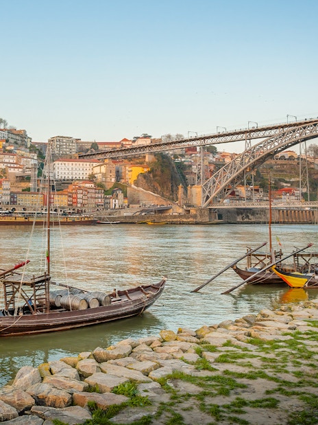 Traditional boats on the Douro River with Dom Luís I Bridge in Porto.