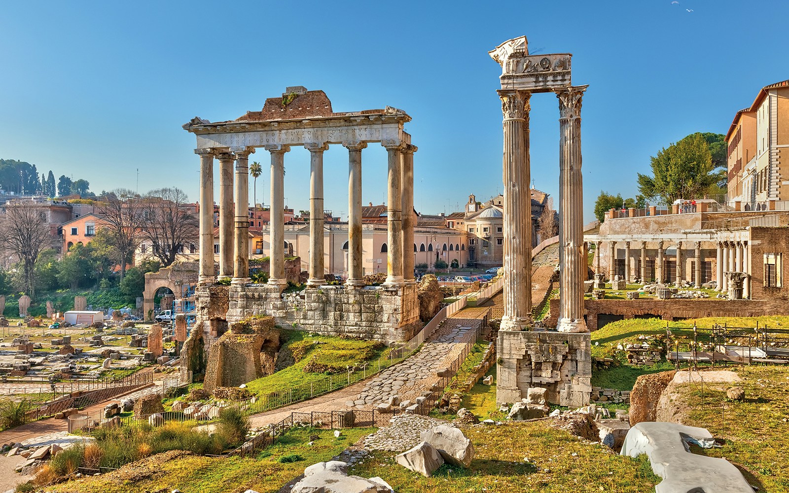 Ancient ruins of the Roman Forum in Rome, Italy, with tourists exploring historical structures.