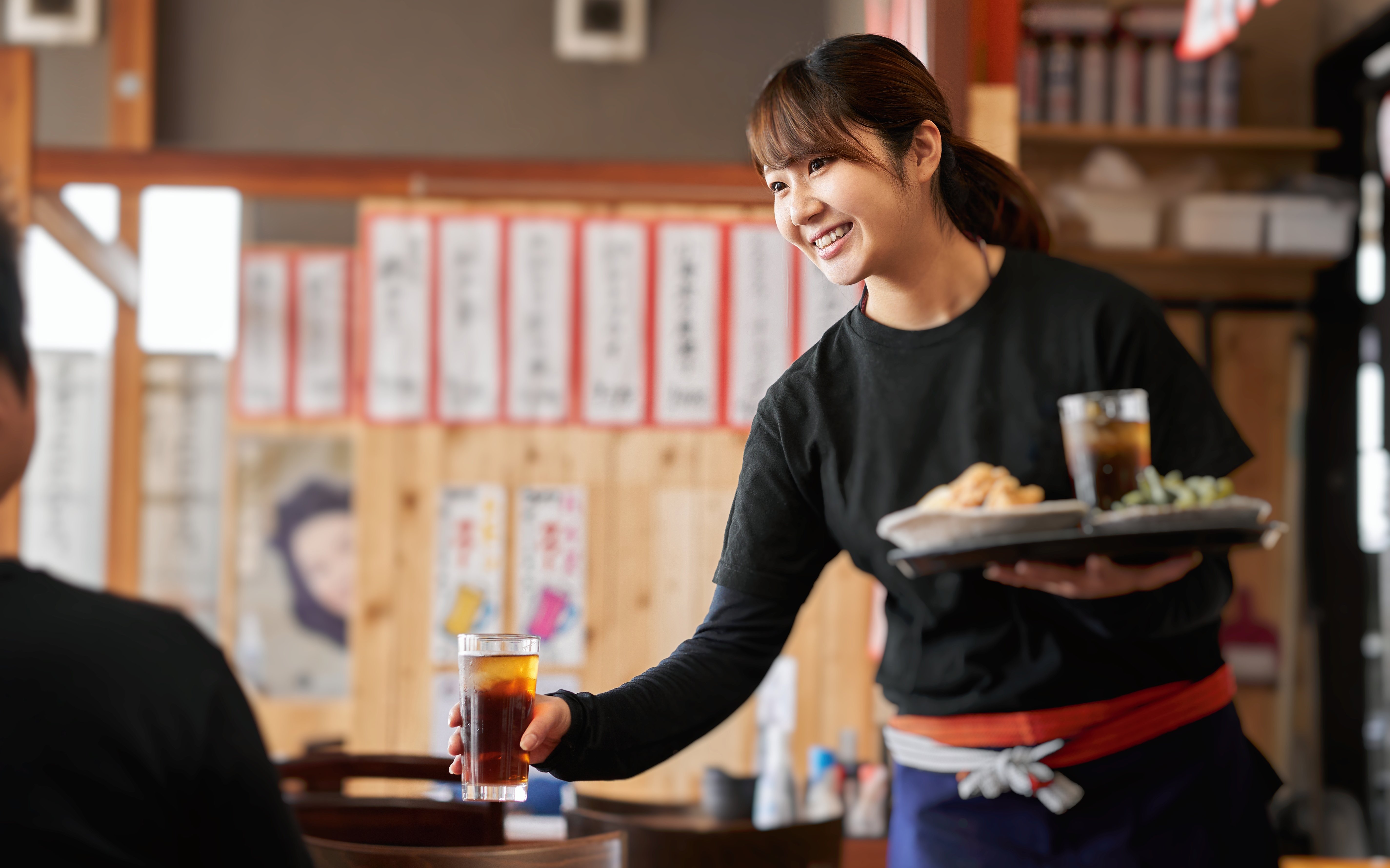 Server delivering drinks and food in a Japanese izakaya pub.