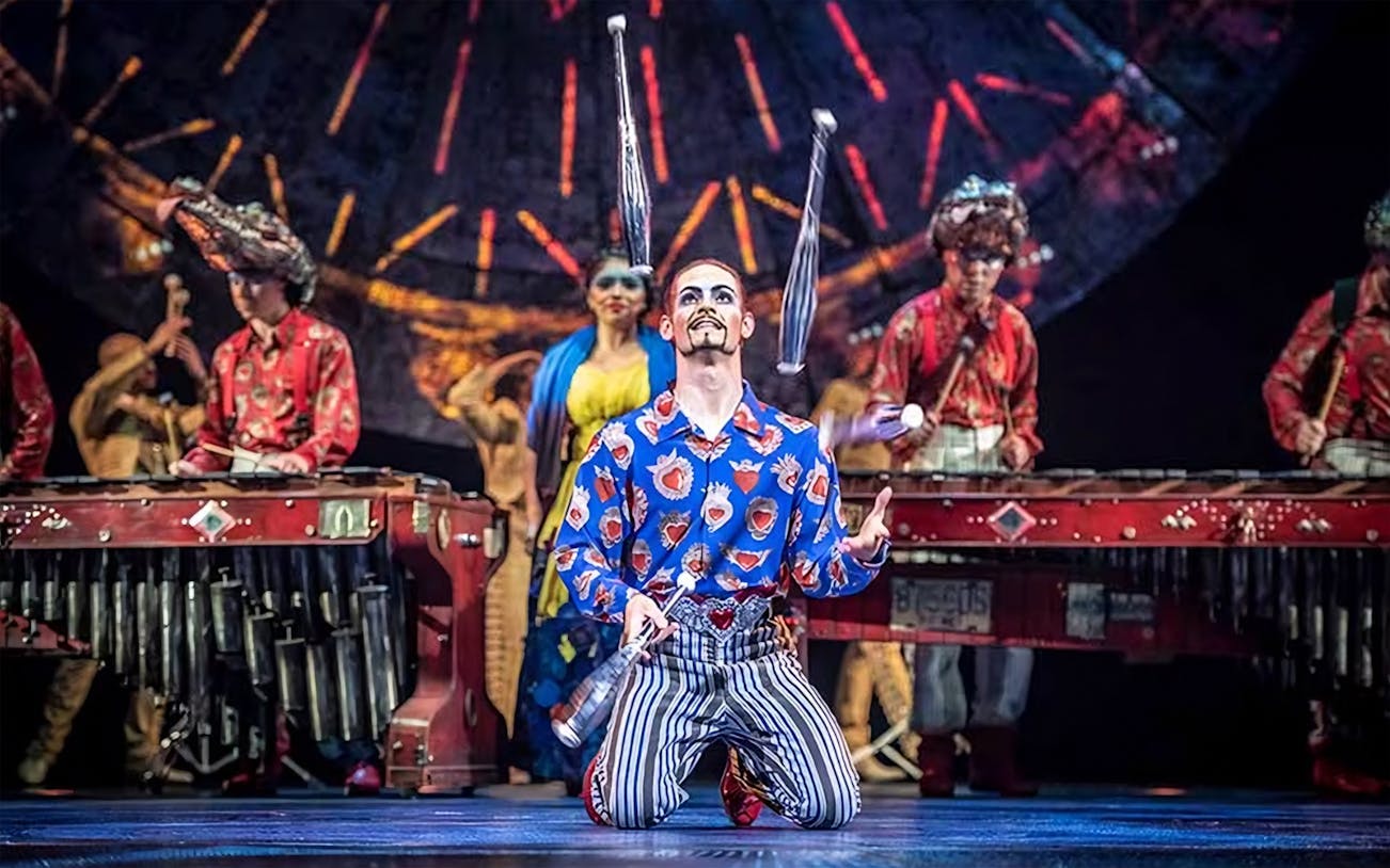 Juggler performing in Luzia show with musicians in the background.