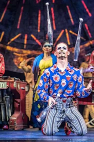Performer juggling on stage during Luzia show with musicians in the background.
