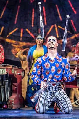 Performer juggling on stage during Luzia show with musicians in the background.