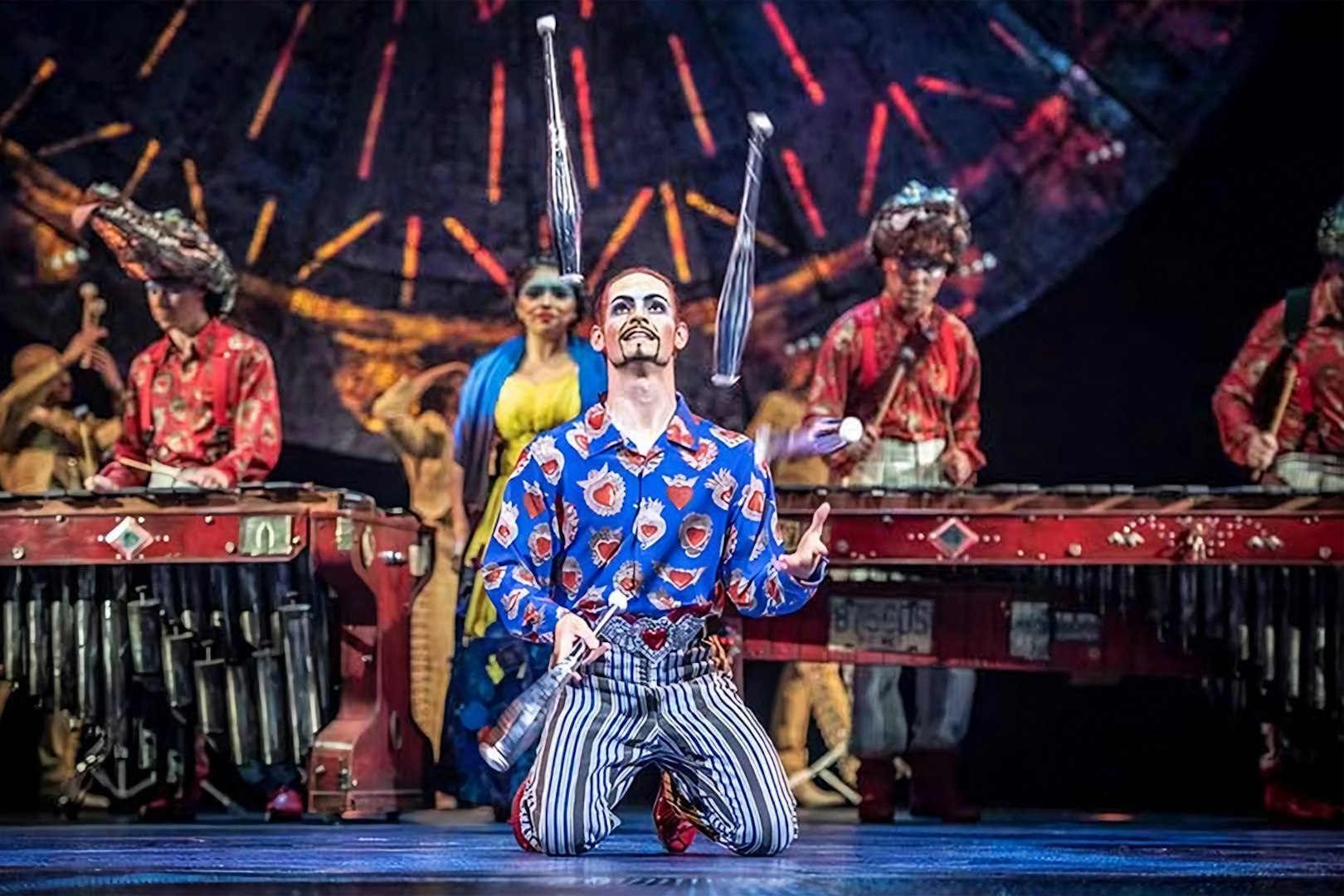 Performer juggling on stage during Luzia show with musicians in the background.