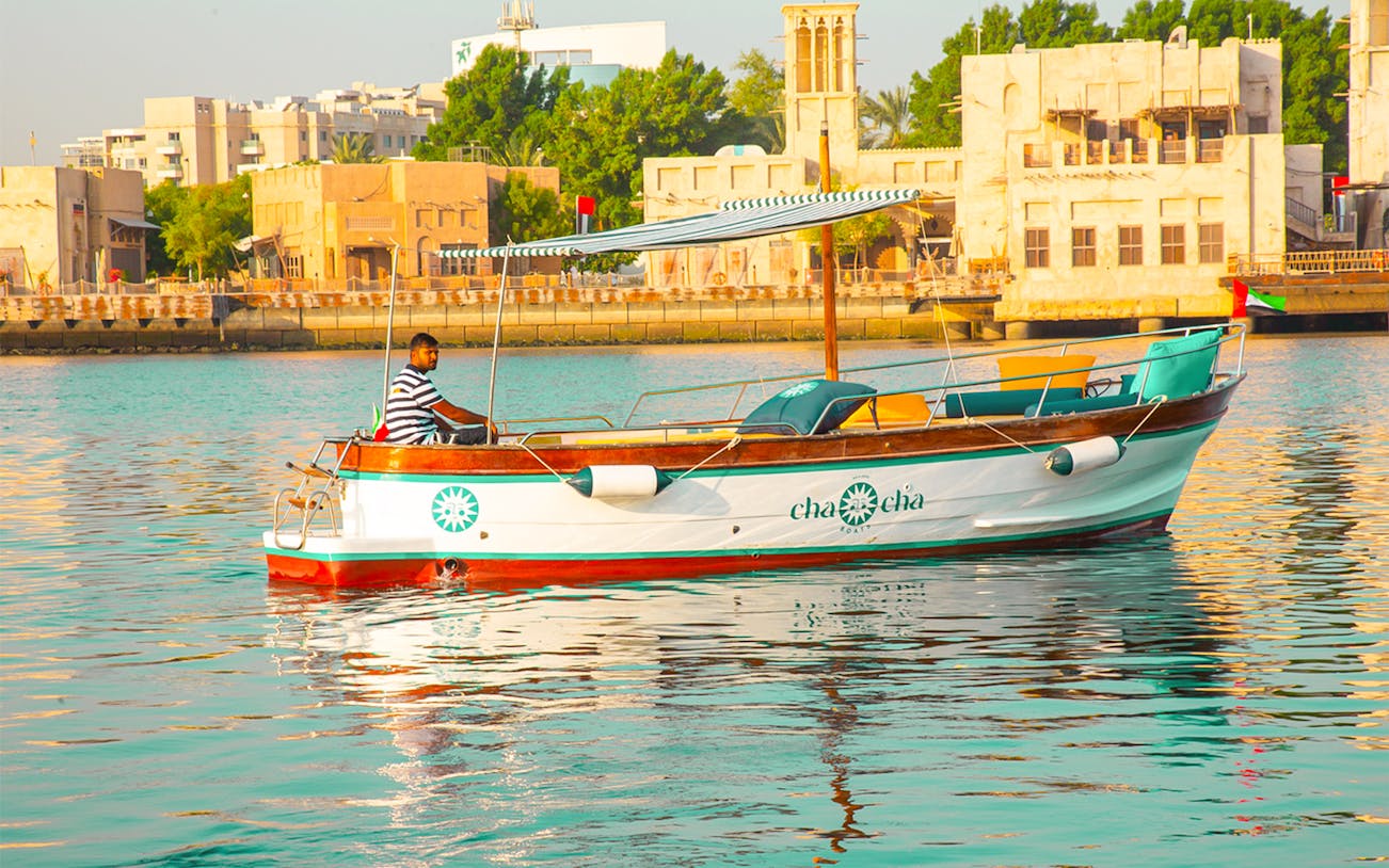 Boat on Dubai Creek with traditional buildings in the background, part of Dubai Historical Tour.