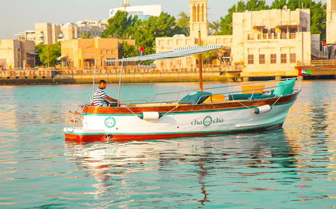 Boat on Dubai Creek with traditional buildings in the background, part of Dubai Historical Tour.