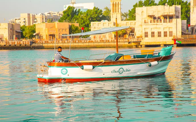 Boat on Dubai Creek with traditional buildings in the background, part of Dubai Historical Tour.