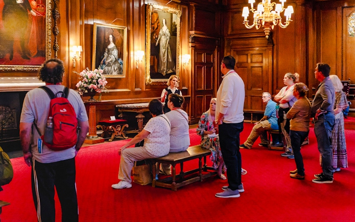 Tour group listening to a guide in the ornate interior of the Palace of Holyroodhouse.