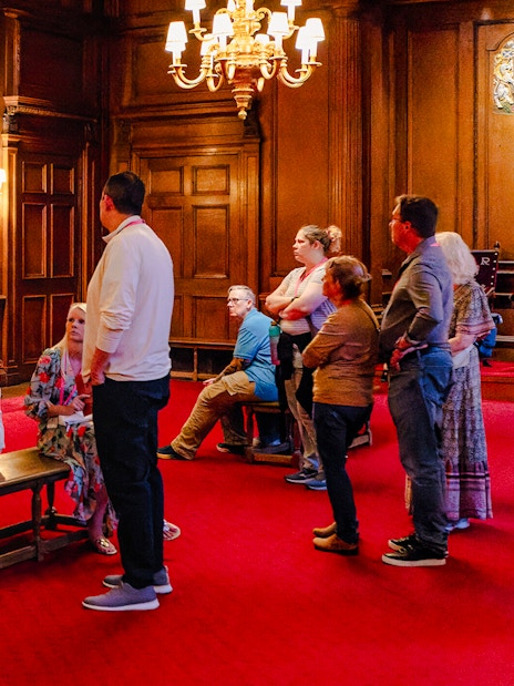 Tour group listening to a guide in the ornate interior of the Palace of Holyroodhouse.