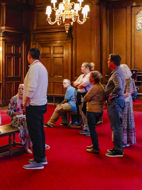 Tour group listening to a guide in the ornate interior of the Palace of Holyroodhouse.