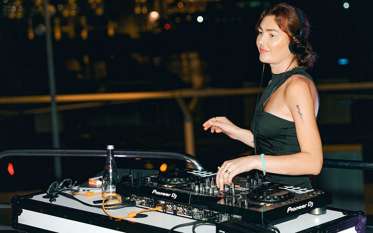 DJ performing on Sunseeker superyacht with music equipment at night.