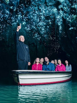 Group on boat tour admiring glowworms in Waitomo Caves, New Zealand.