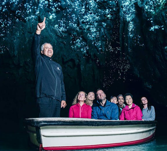 Group on boat tour admiring glowworms in Waitomo Caves, New Zealand.