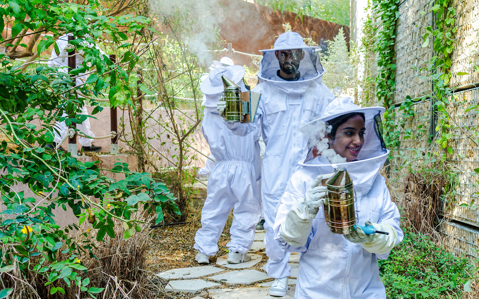 Beekeepers in protective suits using smokers at Terra, Expo City Dubai.