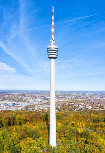 Stuttgart TV Tower rising above autumn trees with cityscape in the background.