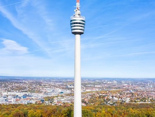 Stuttgart TV Tower rising above autumn trees with cityscape in the background.