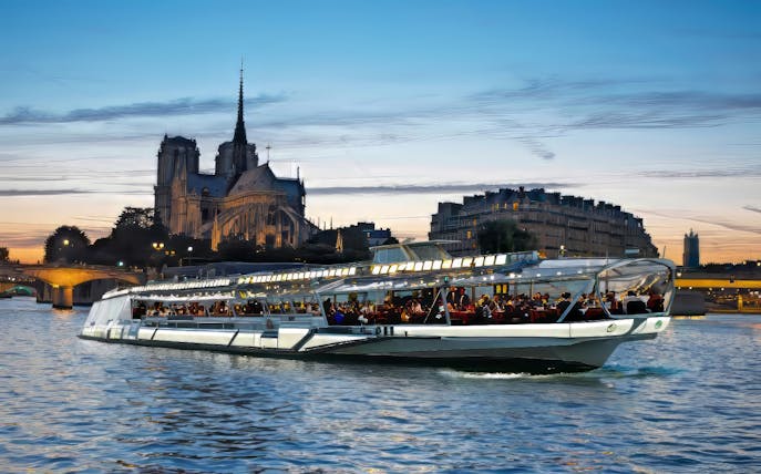 Dinner cruise on the Seine River with Notre-Dame Cathedral in the background, Paris.