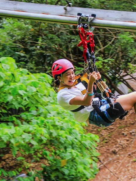 Tourist ziplining at Hanuman World amidst lush greenery.