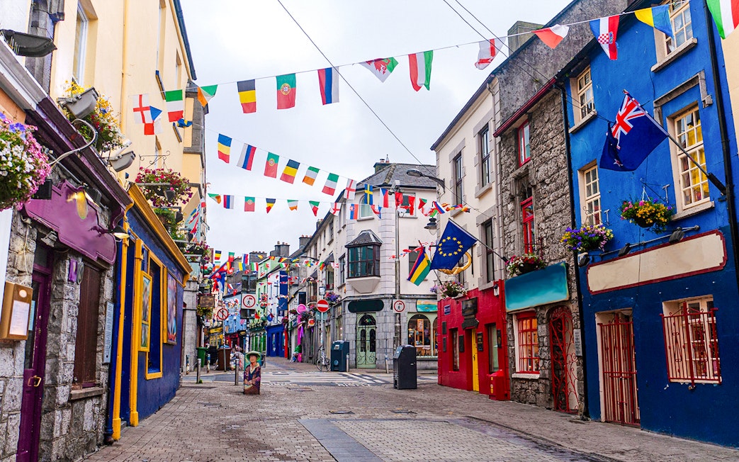 Colorful buildings and international flags on Galway City's main street.