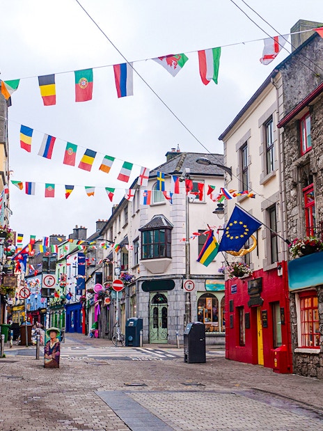 Colorful buildings and international flags on Galway City's main street.