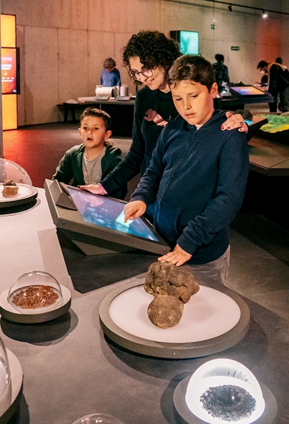 Visitors exploring interactive exhibits at Espai Crater museum.