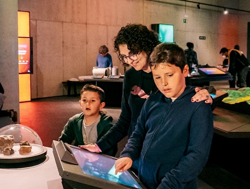 Visitors exploring interactive exhibits at Espai Crater museum.