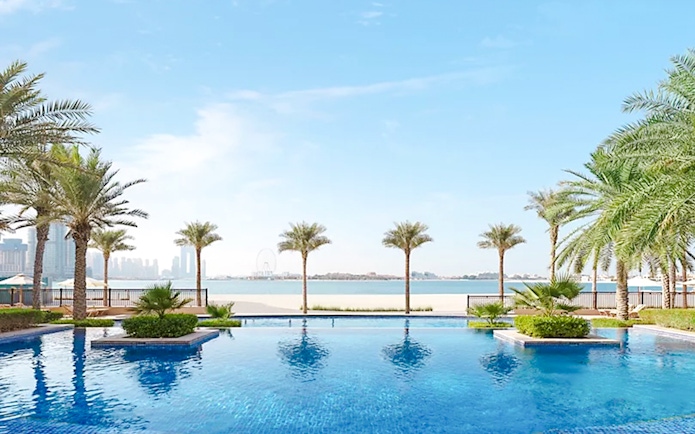 Swimming pool with palm trees at Fairmont Hotel overlooking the city skyline.