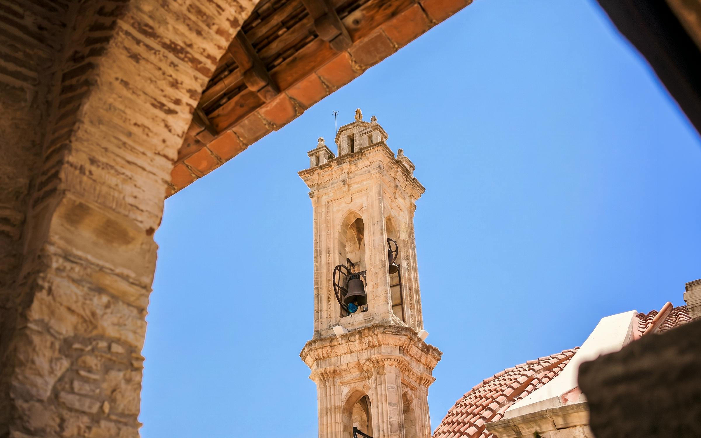 Bell tower in Troodos Mountains village, Cyprus, viewed through an archway.