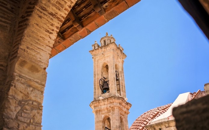 Bell tower in Troodos Mountains village, Cyprus, viewed through an archway.