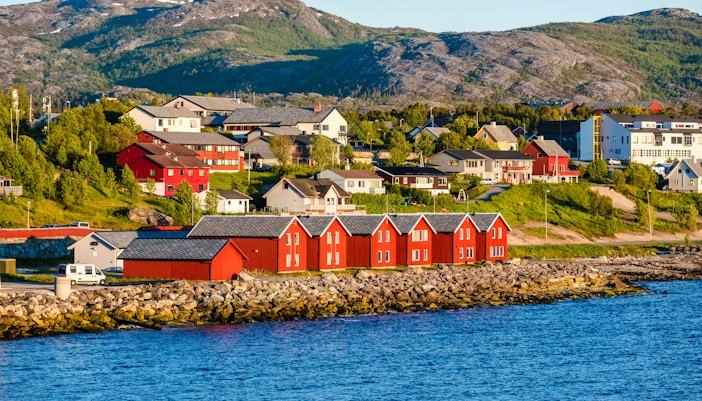 Red houses along the bay in Alta, Norway, with mountains in the background.