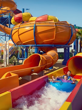 Family enjoying a colorful water slide at Dubai Legoland Waterpark.