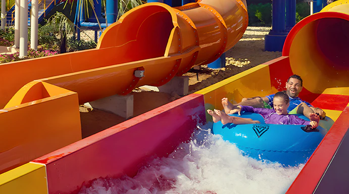 Family enjoying a colorful water slide at Dubai Legoland Waterpark.