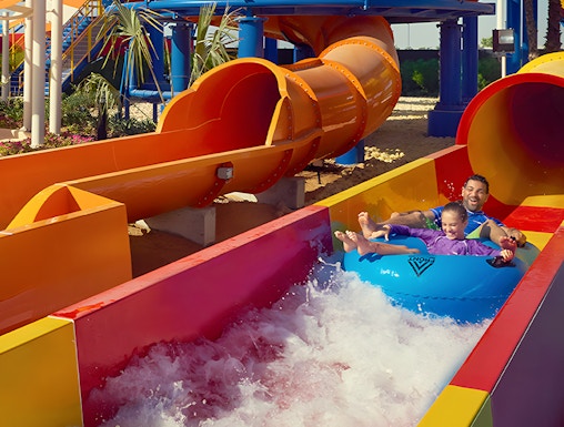 Family enjoying a colorful water slide at Dubai Legoland Waterpark.