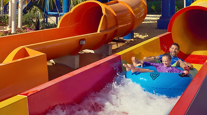 Family enjoying a colorful water slide at Dubai Legoland Waterpark.