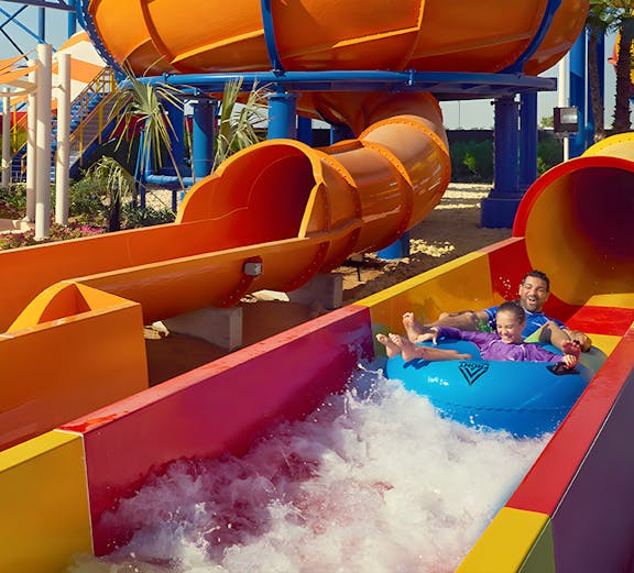 Family enjoying a colorful water slide at Dubai Legoland Waterpark.