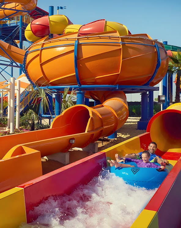 Family enjoying a colorful water slide at Dubai Legoland Waterpark.