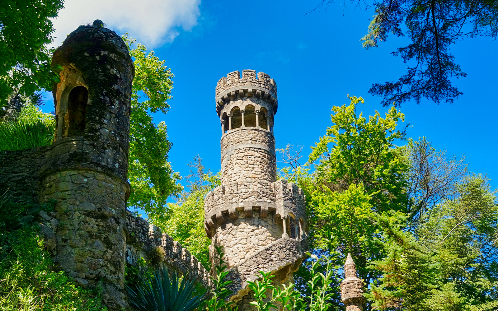 Tower surrounded by greenery in the garden of Quinta da Regaleira, Sintra, Portugal.