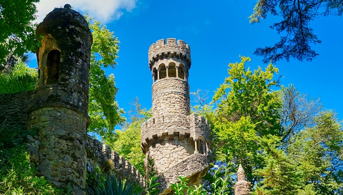 Tower surrounded by greenery in the garden of Quinta da Regaleira, Sintra, Portugal.