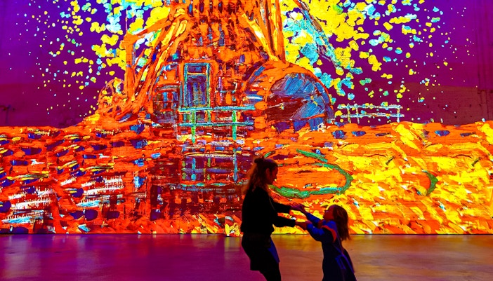 Visitors enjoying vibrant digital art display at Fabrique des Lumières.