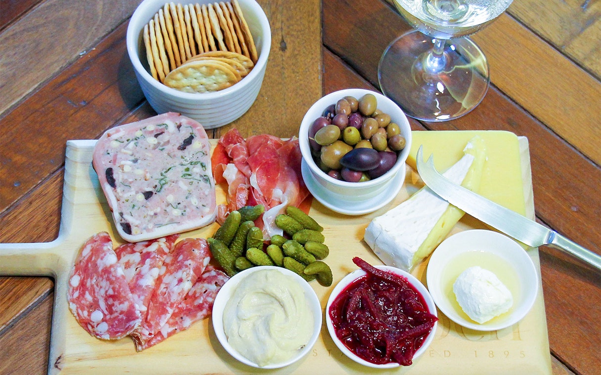 Tulloch Wines cheese board with cured meats, olives, and wine glass in Hunter Valley.
